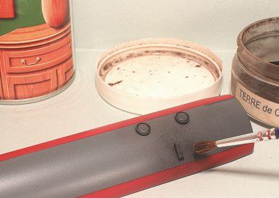 Nos opérations de patine débuteront par les aérateurs et cheminée des cuisines. Une pointe de terre à décor «terre de Cassel» fixée au vernis mat suffira à rehausser ces éléments.