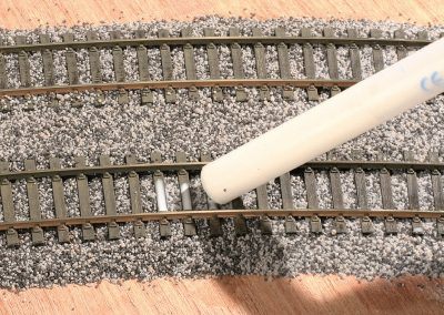 18-La colle est délicatement appliquée sur le ballast en commençant par le milieu de voie.