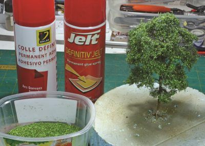 21 – Encollage par petits jets successifs sur les touffes, puis application des petits copeaux de bois teintés.