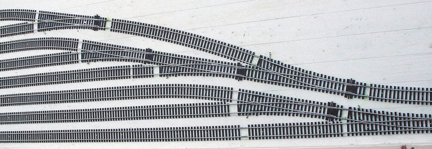 B–Une multiplication d’aiguilles est nécessaire pour desservir un faisceau important. Il faut trouver le compromis dans les angles de déviation des appareils et la place disponible. Il vaut mieux se priver d’une voie supplémentaire pour éviter d’employer des rayons trop serrés, souvent à l’origine de déraillement.